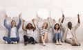 Group of friends sitting on floor, holding speech bubbles above Royalty Free Stock Photo