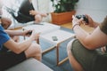 Group of friends sitting on a sofa in living room and playing video games. Family relaxing time at home concept. Royalty Free Stock Photo