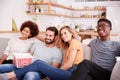 Group Of Friends Sitting On Sofa And Watching Movie At Home Whilst Eating Popcorn Royalty Free Stock Photo