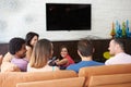 Group Of Friends Sitting On Sofa Watching TV Together