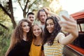 A group of friends with smartphone on a roadtrip through countryside, taking selfie. Royalty Free Stock Photo