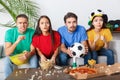 Group of friends sport fans watching concentrated match in colorful shirts Royalty Free Stock Photo