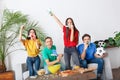 Group of friends sport fans watching match in colorful shirts holding horns and hand clappers Royalty Free Stock Photo