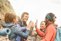 Group of friends stacking hands while doing trekking excursion on mountain - Young tourists having fun exploring the wild nature