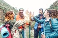 Group of friends stacking hands while doing trekking excursion on mountain - Young tourists walking and exploring the wild nature Royalty Free Stock Photo