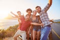 Group Of Friends Standing By Car On Coastal Road At Sunset Royalty Free Stock Photo