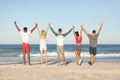 Group of friends standing together with hands raised on the beach Royalty Free Stock Photo