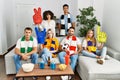 Group of friends supporting football team watching tv al home sitting on the sofa thinking attitude and sober expression looking Royalty Free Stock Photo