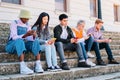 Group of friends surf in social media with their phones sitting together on the street. Royalty Free Stock Photo