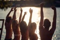 A group of friends in swimsuit is enjoying the sunset on the bank of the river. Summer, river, vacation