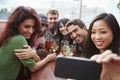 Group Of Friends Taking Photograph At Outdoor Rooftop Bar