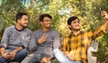 Group of friends taking a self portrait in the park - Concept of young people addicted to selfie - Three friends are sitting on Royalty Free Stock Photo