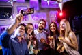 Group of friends taking selfie while having glasses of cocktail