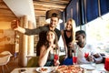 Group of friends taking selfie on a smart phone. Young people eating pizza on rooftop party taking selfie. Royalty Free Stock Photo