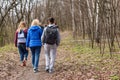 Group of friends walking with backpacks in spring forest from back. Backpackers hiking in the woods. Adventure, travel Royalty Free Stock Photo