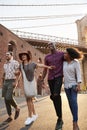 Group Of Friends Walking By Brooklyn Bridge In New York City