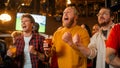 Group of Friends Watching a Live Soccer Match on TV in a Sports Bar. Three Men Cheering and Shouting Royalty Free Stock Photo