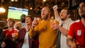 Group of Friends Watching a Live Soccer Match on TV in a Sports Bar. Three Men Cheering and Shouting