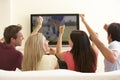 Group Of Friends Watching Widescreen TV At Home Royalty Free Stock Photo