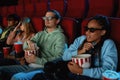 A group of friends wearing glasses, looking emotional while watching horror movie together in cinema auditorium Royalty Free Stock Photo