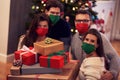 Group of friends wearing masks exchanging Christmas presents at home Royalty Free Stock Photo