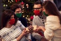 Group of friends wearing masks exchanging Christmas presents at home Royalty Free Stock Photo