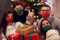 Group of friends wearing masks exchanging Christmas presents at home Royalty Free Stock Photo