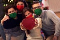 Group of friends wearing masks exchanging Christmas presents at home Royalty Free Stock Photo