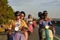 Group of friends wearing protective helmets while riding vintage moto scooters together outside the city