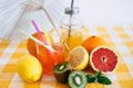 Group of fruits rich in vitamins. Citrus fruits and kiwi. Fruit juice. Yellow checkered tablecloth and white umbrella. Healthy Royalty Free Stock Photo