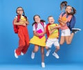 Group of funny excited classmates girls and boy with backpacks and copybooks jumping up in air Royalty Free Stock Photo