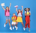 Group of funny excited classmates girls and boy with backpacks and copybooks jumping up in air Royalty Free Stock Photo