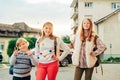 Group of 3 funny kids with backpacks, 2 schoolgirls and one preschooler