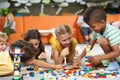 Group of funny kids playing with block toys indoor.