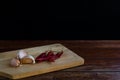 garlic on chopping board and red dried chilli on wooden table with black background. Copy space for your text