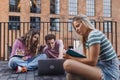 Group of generation Z students studying together outdoors after school. Young stylish zoomers working together on school