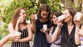 Group of girlfriends toasting with champagne in paper glass. Young people celebrating with champagne at party outdoors. Concept of