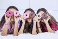 Group of girls covers their eyes with donuts in bed