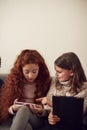 Group Of Girls With Friends Sitting On Sofa At Home Playing On Digital Tablet And Mobile Phones Royalty Free Stock Photo