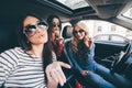 Group of girls having fun in the car and taking selfies with camera on road trip Royalty Free Stock Photo