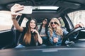 Group of girls having fun in the car and taking selfies with camera Royalty Free Stock Photo