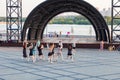 A group of girls is recording a dance for the kippah on the embankment of the square against the background of the stage, a guy