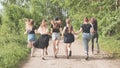 A group of girls run along the village road by the forest holding hands. Royalty Free Stock Photo