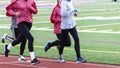 Group of girls running on a red track in the cold Royalty Free Stock Photo