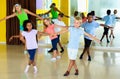 Group of children practicing vigorous jive movements in dance class with female coach Royalty Free Stock Photo