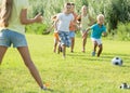 Group of glad kids playing football together on green lawn in park Royalty Free Stock Photo