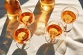 Group of glasses with amber wine, radiating a rich, deep orange hue on a table with beige fabric. Minimalist trendy style. Gentle