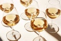 Group of glasses with white wine, radiating a rich, deep orange hue on a light beige table. Minimalist trendy style. Gentle