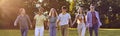 Group of happy young diverse people holding hands and walking in a green park in summer Royalty Free Stock Photo