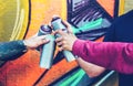 Group of graffiti artists stacking hands while holding spray color can against mural background - Young painter at work Royalty Free Stock Photo